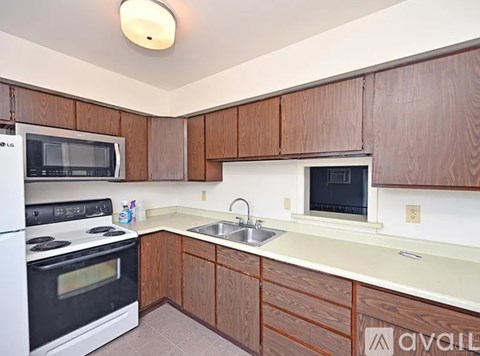 A kitchen with wooden cabinets and a white stove top oven.