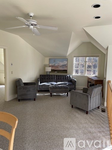 A living room with a grey couch and a fan.
