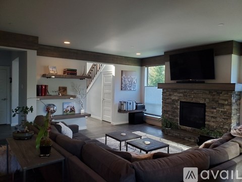 A living room with a brown couch and a stone fireplace.