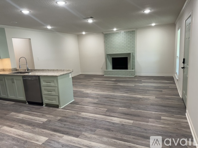 A kitchen with a wooden floor and a brick fireplace.