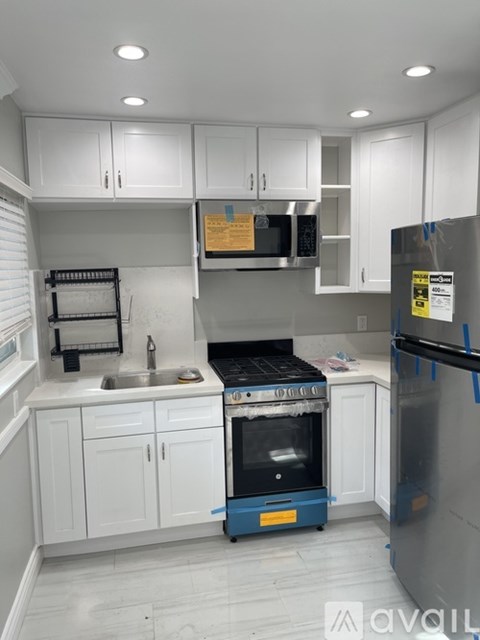 A kitchen with white cabinets and a blue cart with a stove on it.
