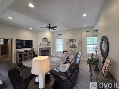 A living room with a black leather couch and a white lamp on a table.