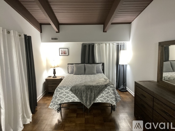 A bedroom with a bed, nightstand, and a mirror.