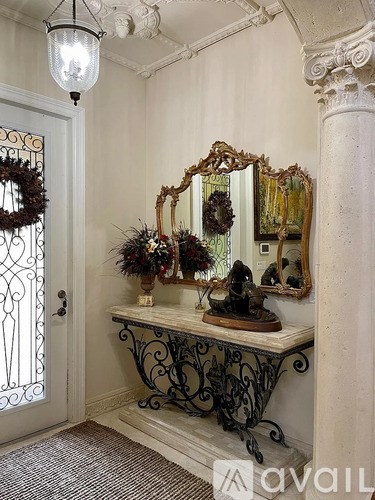 A white and black console table with a mirror and a wreath on it.