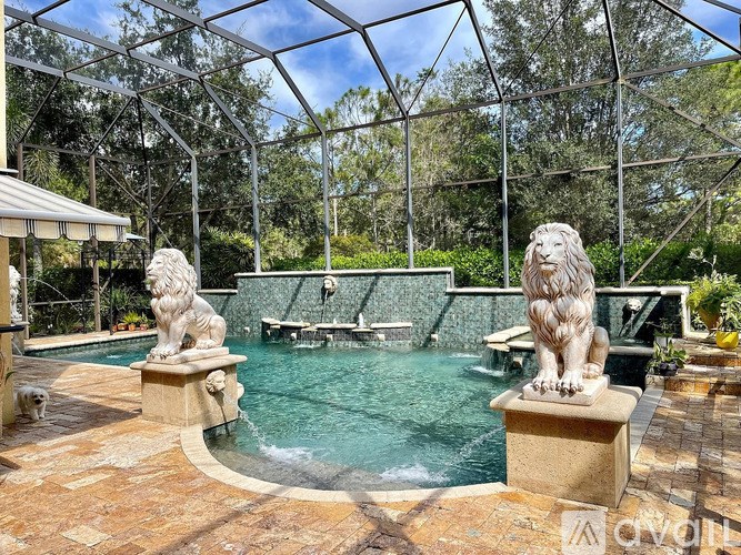A pool surrounded by a glass wall with a lion statue on the side.