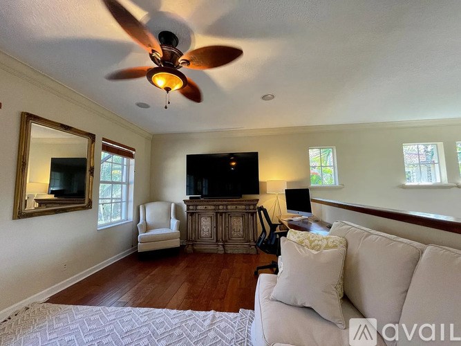 A living room with a white couch and a ceiling fan.