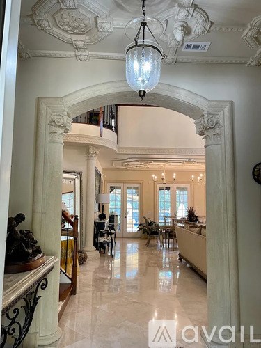 A hallway with a light hanging from the ceiling and a balcony with plants.