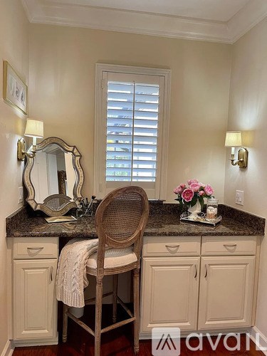 A vanity with a chair and a mirror is set up in a room.