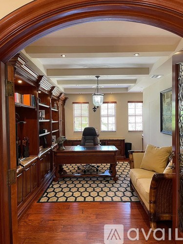 A living room with a wooden floor and a black and white patterned rug.