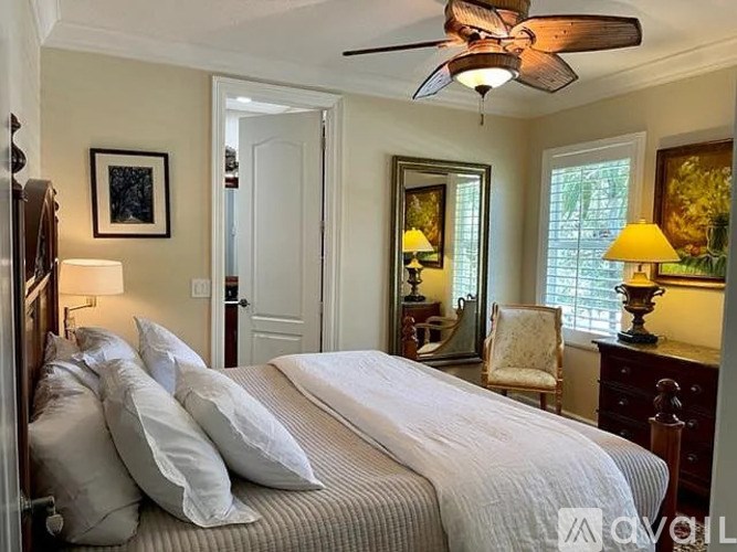 A bedroom with a bed, a chair, and a ceiling fan.