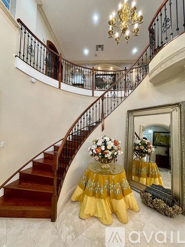 A grand staircase with a chandelier and a mirror reflecting a yellow dress.