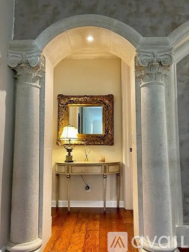 A room with a large mirror and a table with a lamp on it.