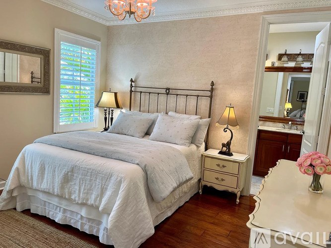 A bedroom with a large bed, a chandelier, and a vanity with a mirror.