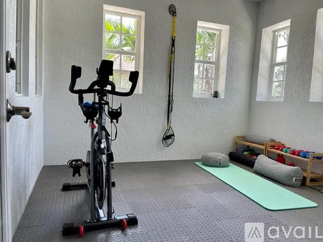 A room with a stationary bike, a yoga mat, and a foam roller.