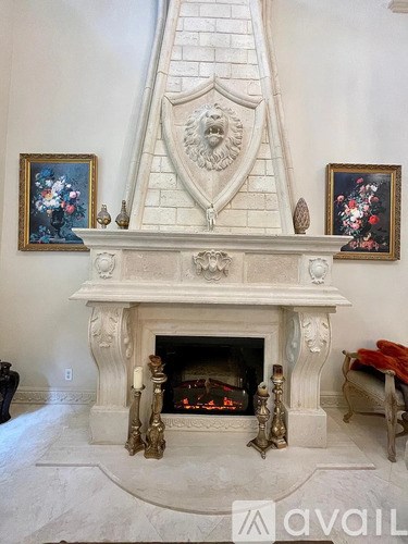 A white marble fireplace with a gold lion head on top.