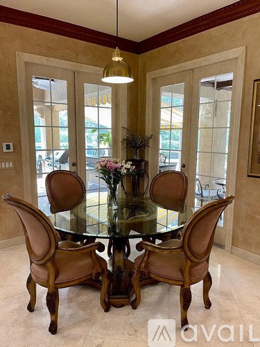 A glass dining table with four chairs and a vase of flowers on top.