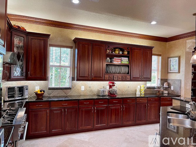 A kitchen with dark wood cabinets and a black counter top.