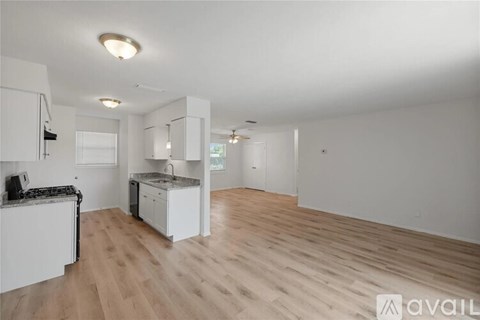 A kitchen with white cabinets and a wooden floor.