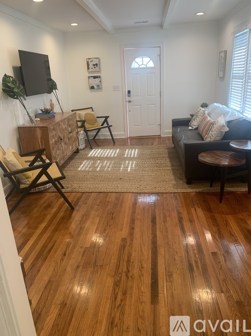 A living room with a wooden floor and a rug in the middle.