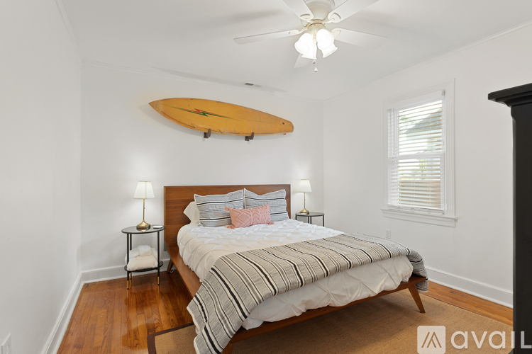 A bedroom with a surfboard on the wall and a bed with a striped comforter.