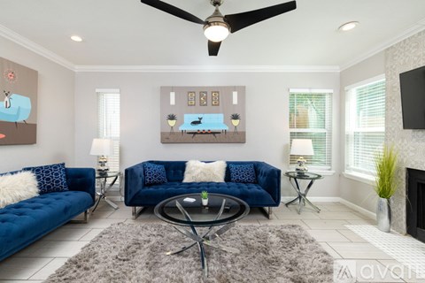 A living room with a blue sofa and a glass coffee table.