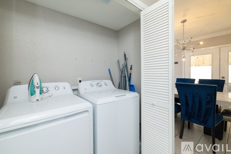 A laundry room with a washer and dryer and a dining area in the background.