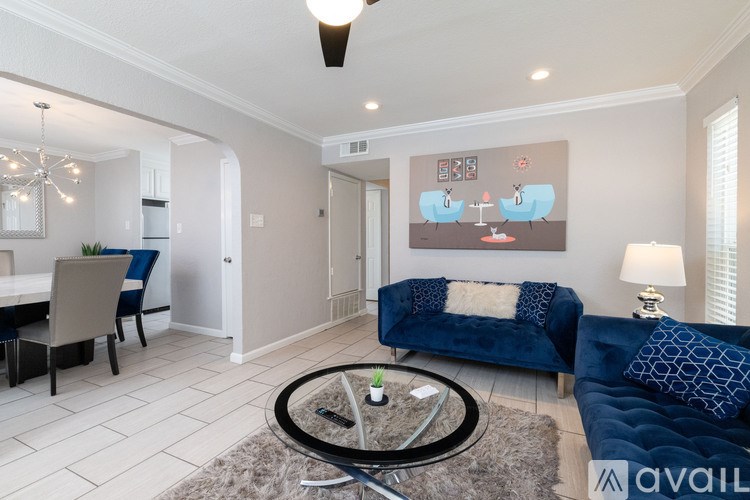 A living room with a blue couch and a painting on the wall.