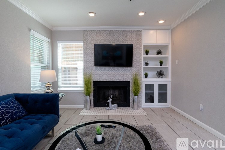 A living room with a blue couch, a fireplace, and a television mounted on the wall.