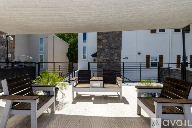 A patio with wooden furniture and a white wall in the background.