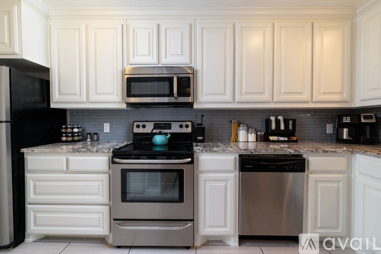A kitchen with black appliances and white cabinets.