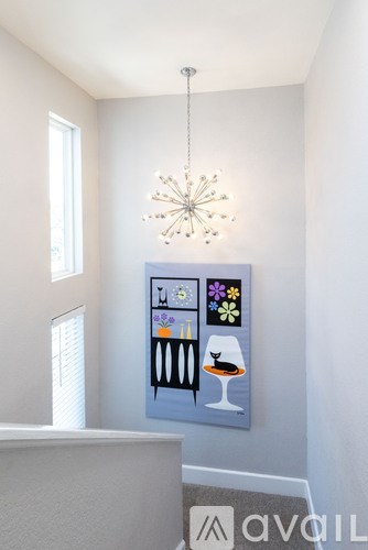 A painting of a bar with a drink and a flower is hanging on the wall.