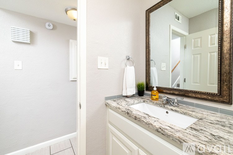 A bathroom with a marble countertop and a large mirror.