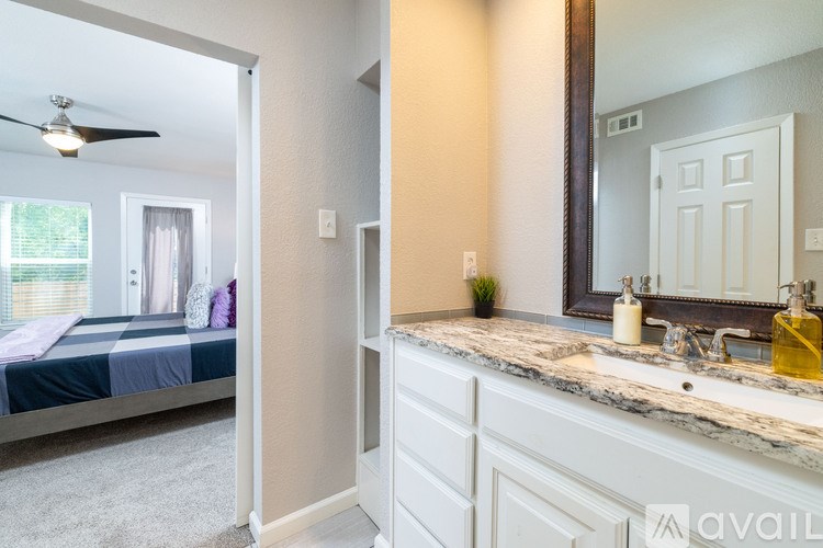 A bedroom with a bed, a mirror, and a fan.