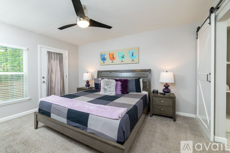 A bedroom with a bed, two lamps, and a ceiling fan.