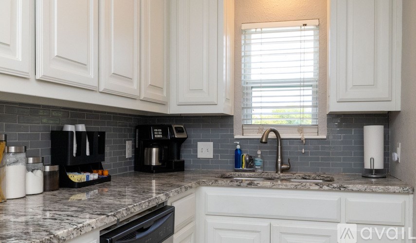 A kitchen with white cabinets and a marble countertop.