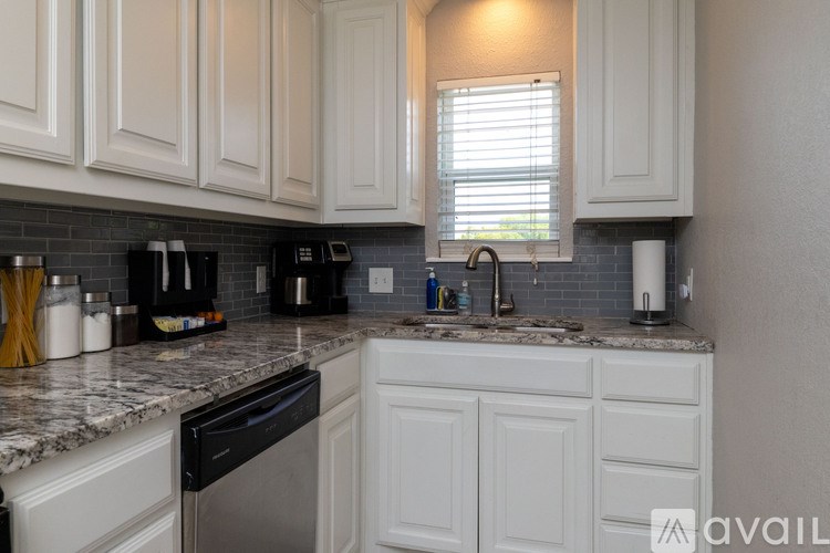 A kitchen with white cabinets and a granite countertop.