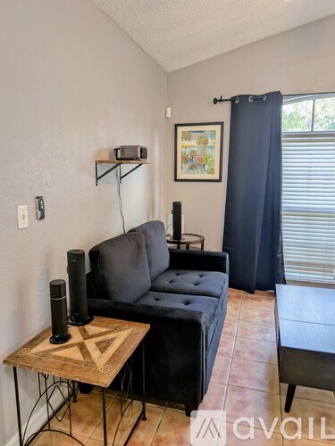 A living room with a black couch and a wooden coffee table.