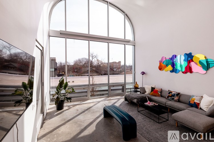 A living room with a large window and a colorful abstract art piece on the wall.