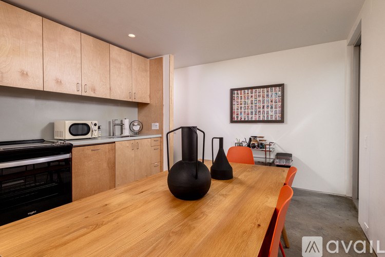 A kitchen with wooden cabinets and a wooden table with two vases on it.