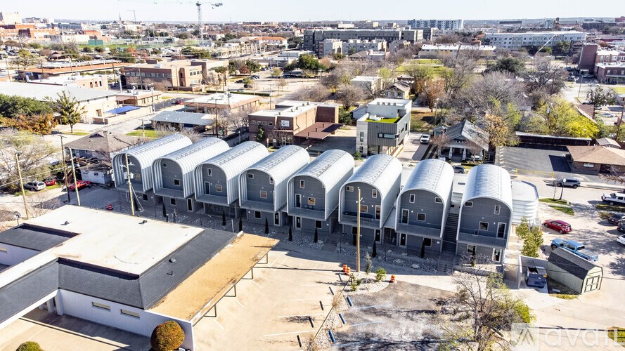 A large industrial building with a white exterior and a curved roof is surrounded by a parking lot.