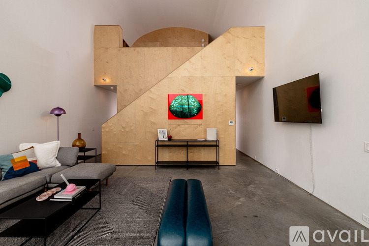A living room with a grey couch, a coffee table, a blue bench, and a painting on the wall.