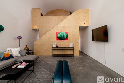 A living room with a grey couch, a coffee table, a blue bench, and a painting on the wall.