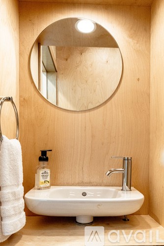 A bathroom with a round mirror and a white sink.
