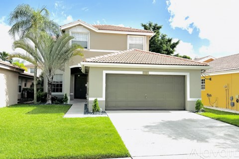 A house with a garage and a driveway in front of it.