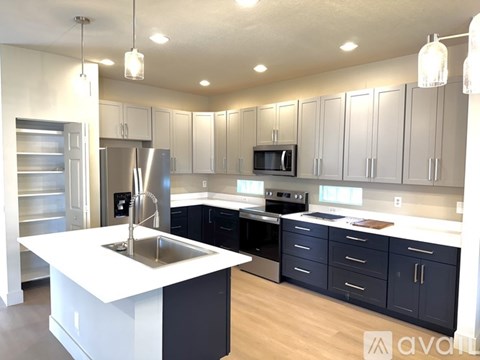 A modern kitchen with a white island and dark blue cabinets.
