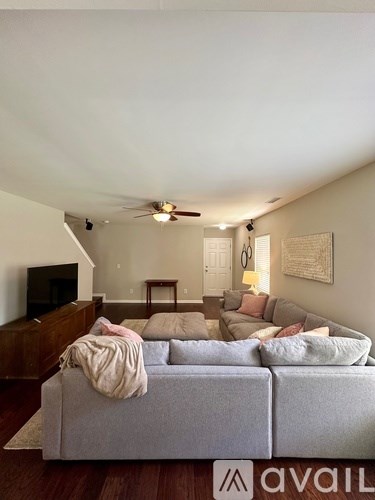 A living room with a grey couch and a television on a wooden cabinet.