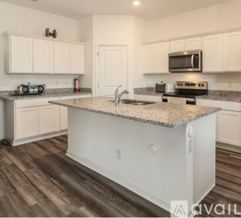 A kitchen with white cabinets and a granite countertop.
