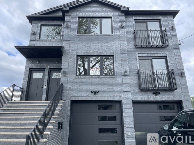 A grey two-story house with a balcony on the second floor.
