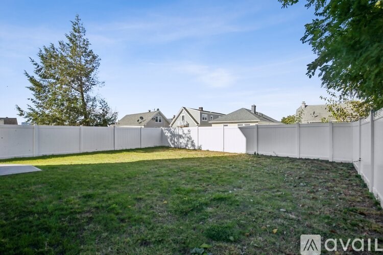A backyard with a white fence and a house in the background.