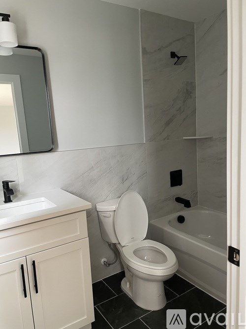 A white toilet in a bathroom with a marble wall.